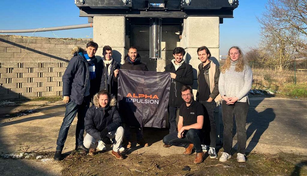 Alpha Impulsion's team posing in front of the engine test bench